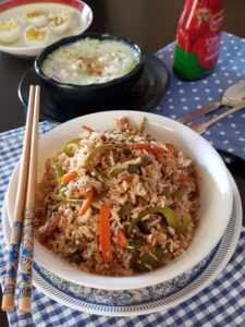 vegetable fried rice in a white bowl with two chopsticks.