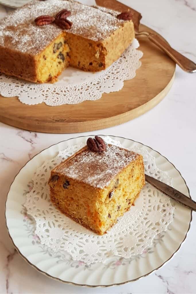 carrot cake cut into a square piece and served on a plate