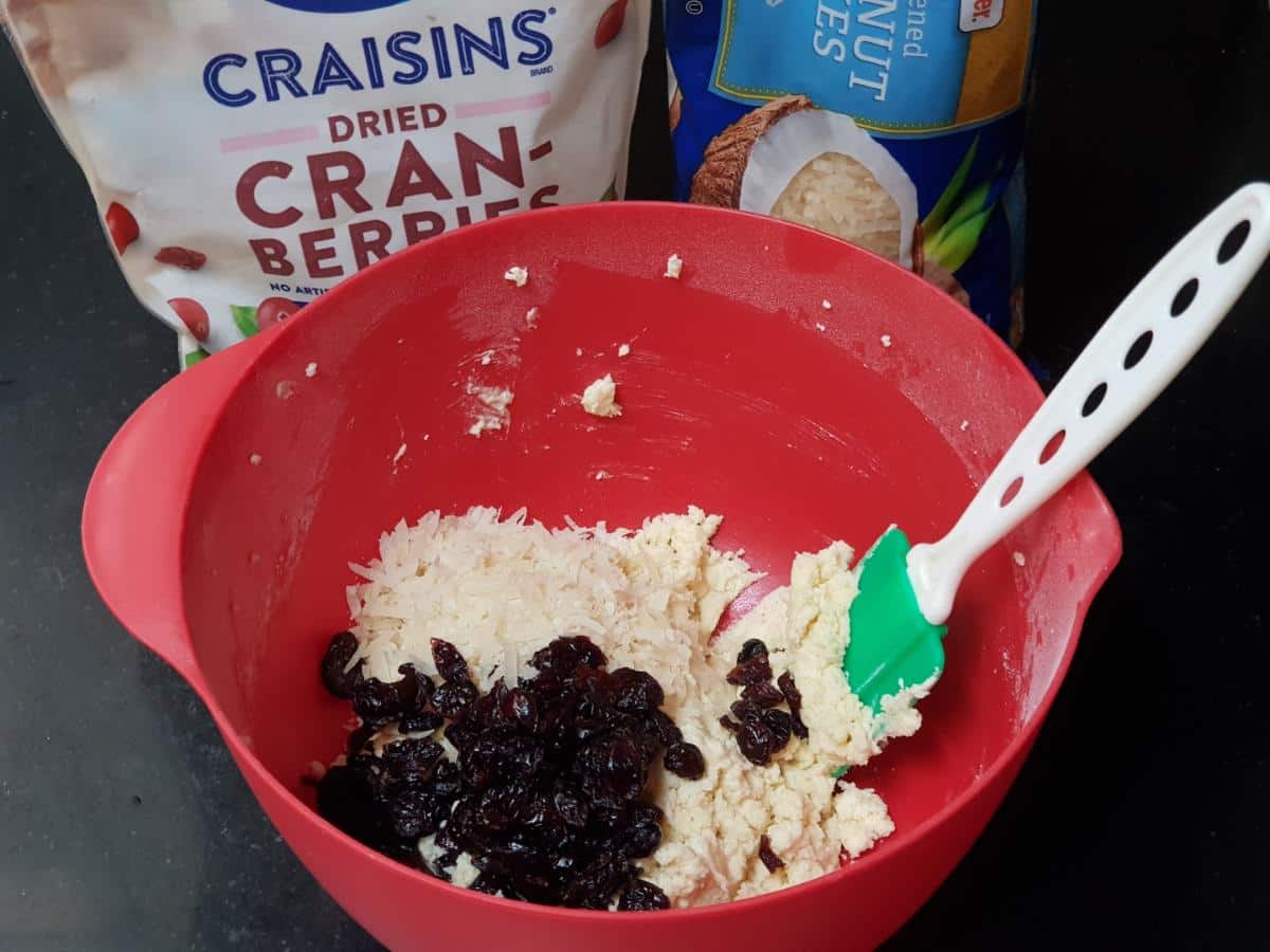 Sweetened coconut flakes and dried cranberries folded into cookie dough