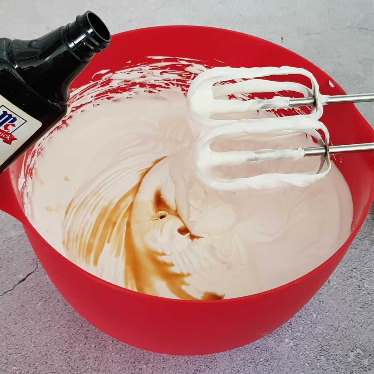 Adding vanilla extract to the whipped cream.