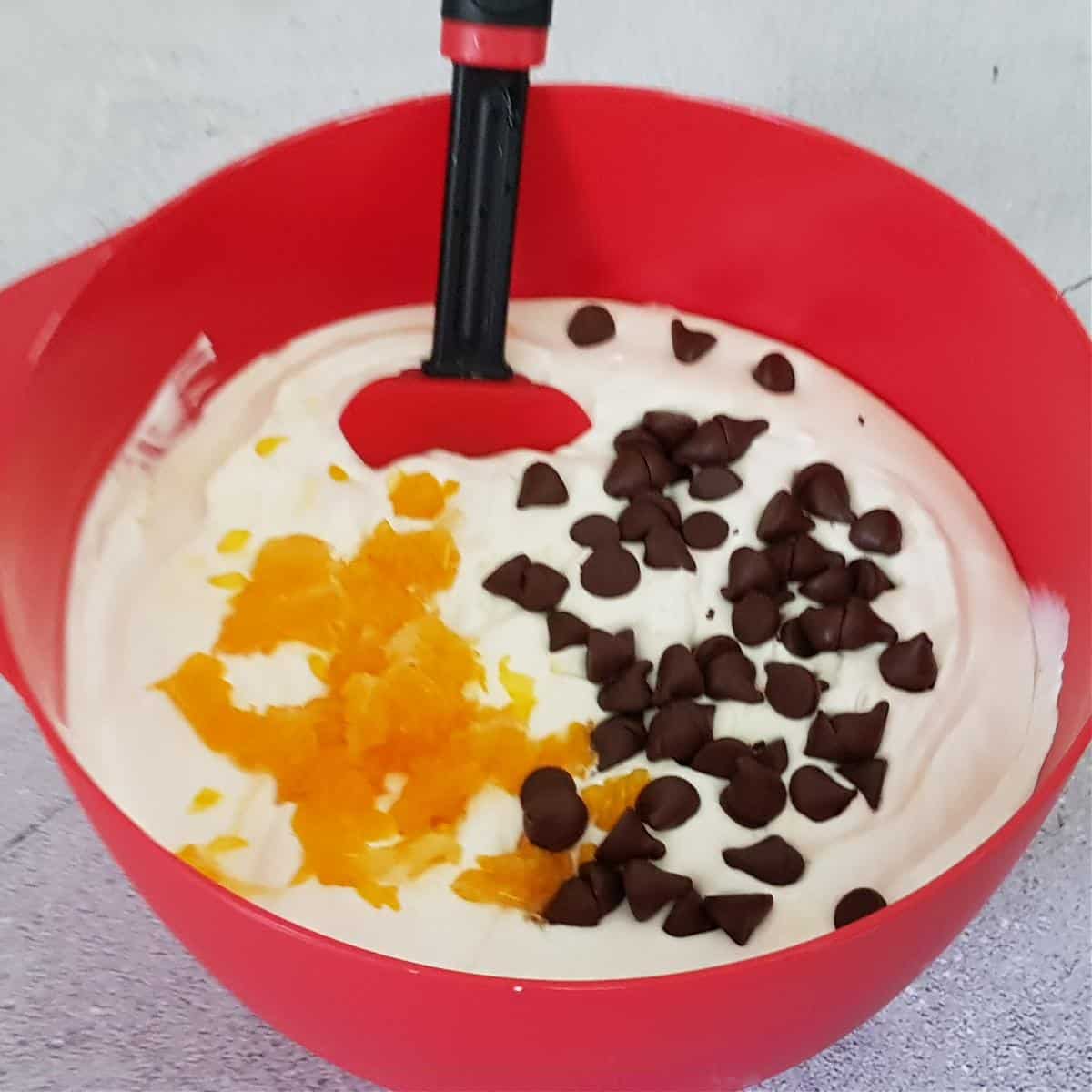 Fold in fresh orange pulp and dark chocolate chips added to the ice cream mixture.