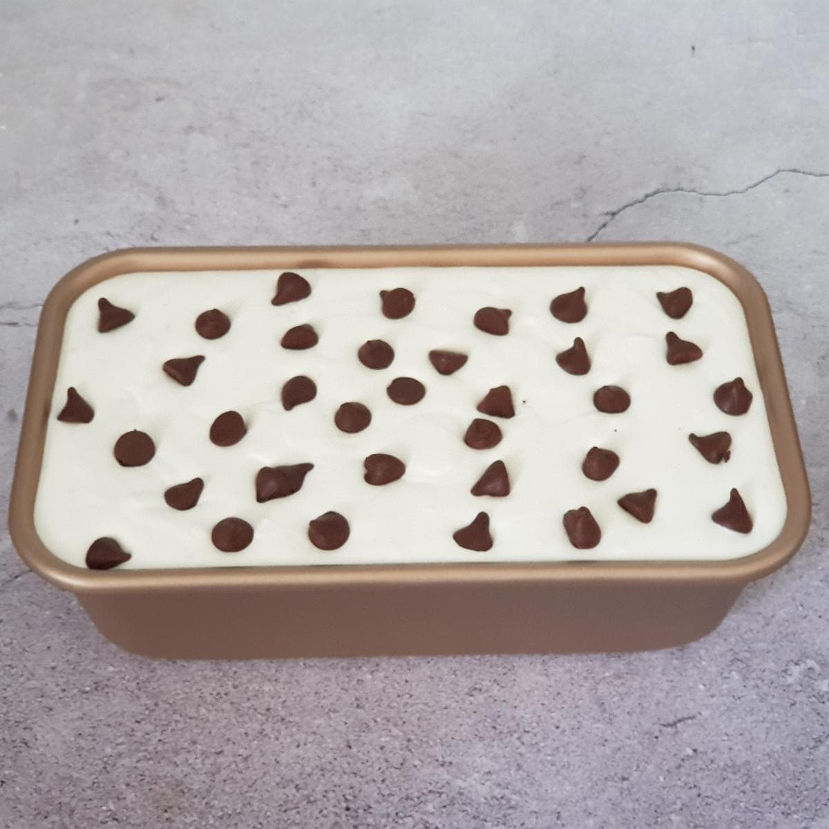 Orange ice cream mixture in a loaf pan ready to freeze.